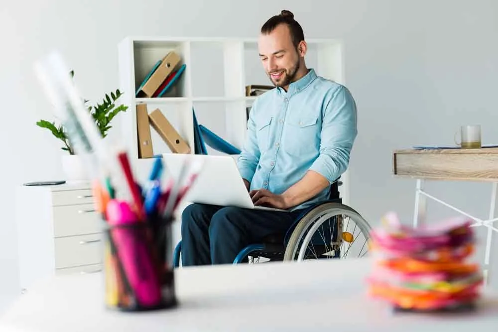 ein Mann im Rollstuhl, der an seinem Laptop arbeitet