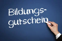 Ein Mann, der das Wort "Bildungsgutschein" auf eine Tafel schreibt