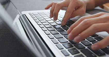 eine Person, die auf einem Laptop Computer tippt